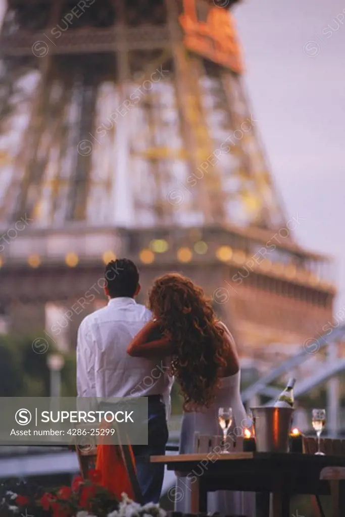 Couple on Seine River houseboat under Eiffel Tower for romantic sunset