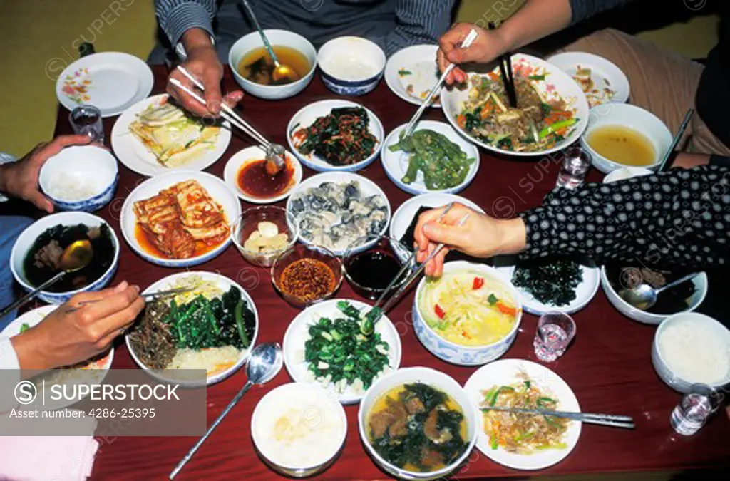 Family eating typical Korean foods at home with chopsticks