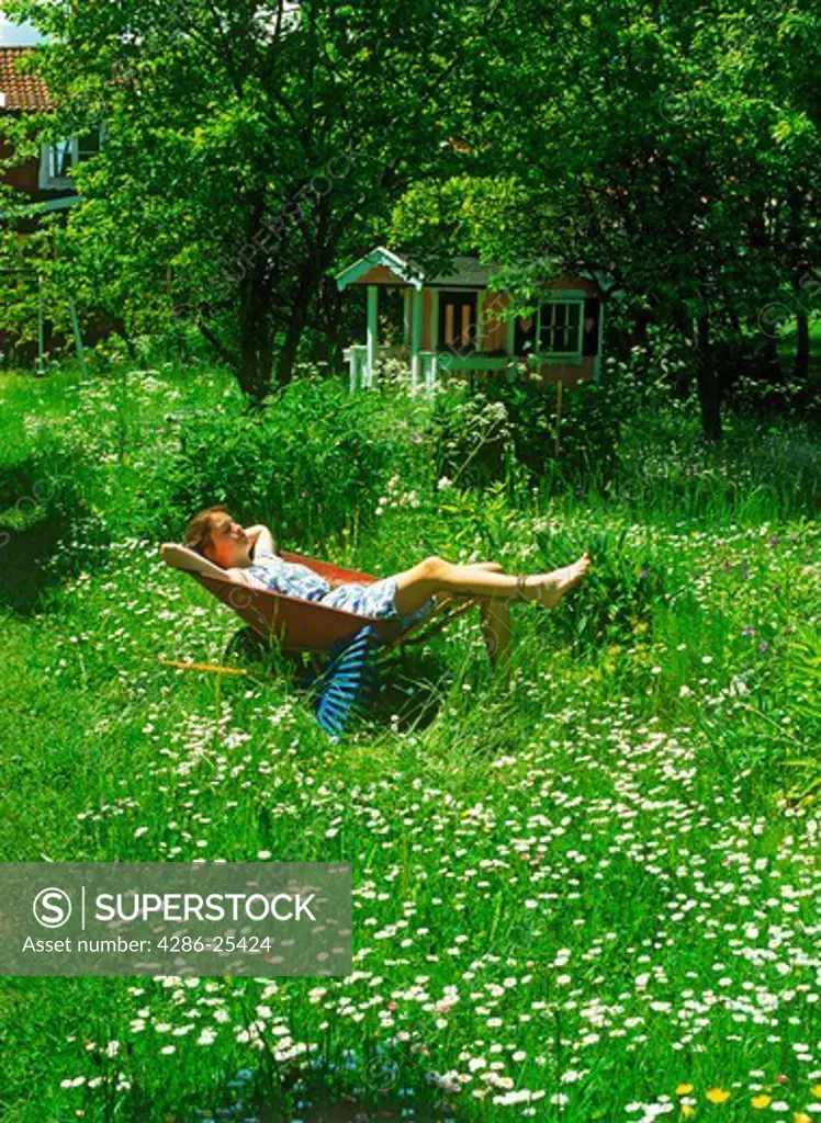Girl resting in wheelbarrow in yard filled with bellis flowers