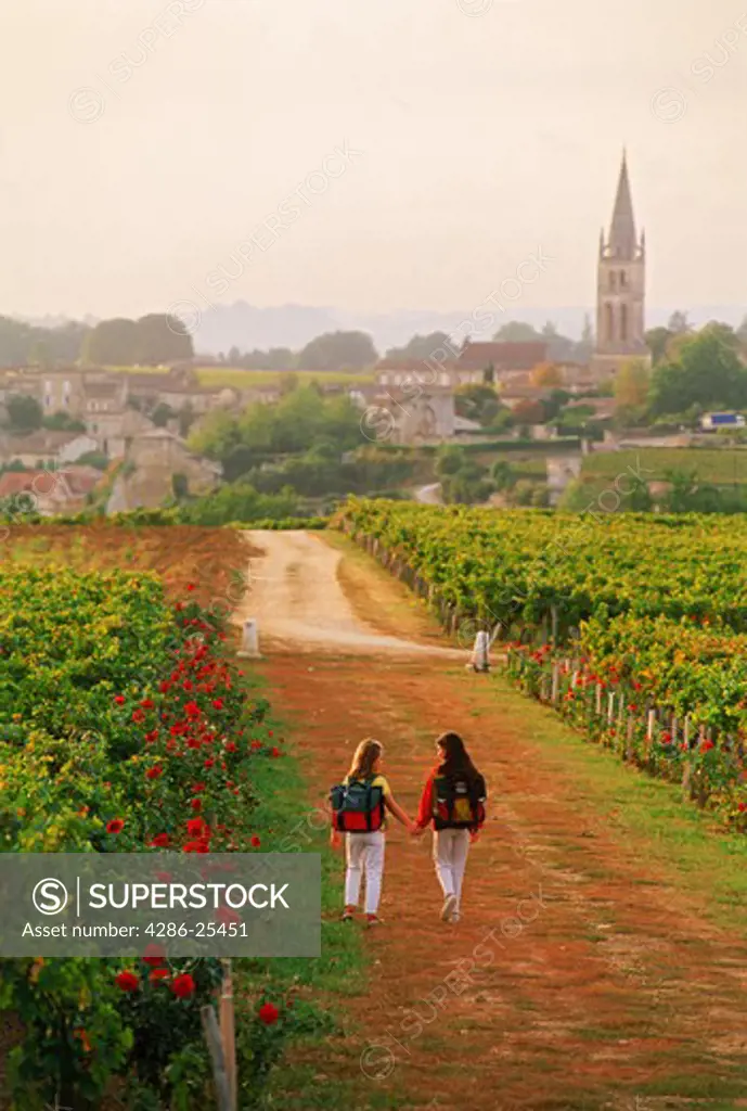 Girls passing through St Emilion vineyards on way to school in France