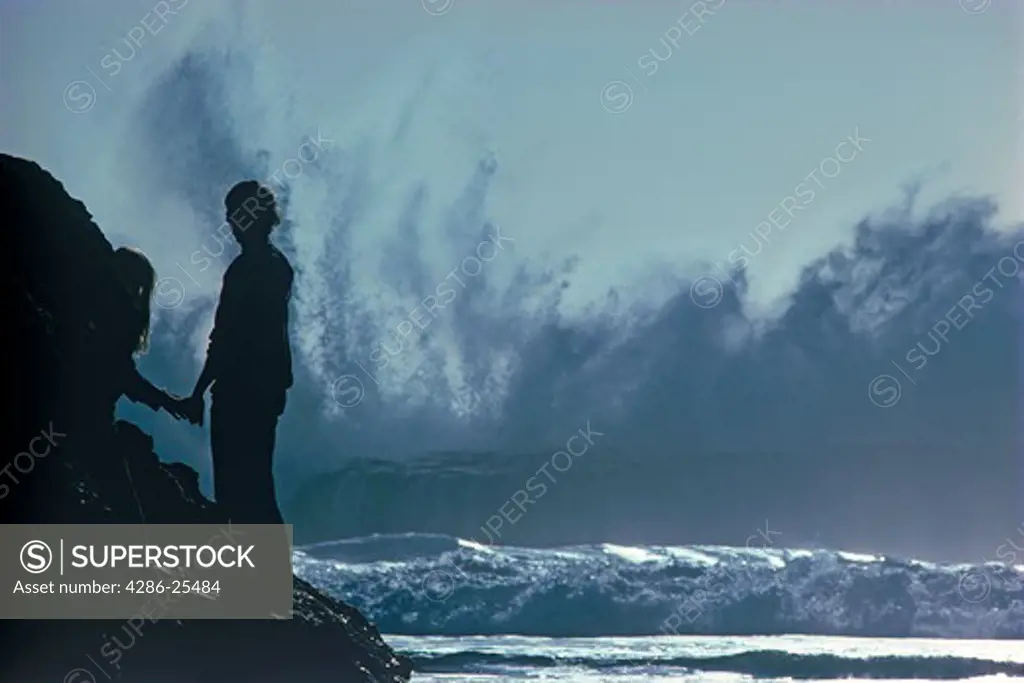 Storm waves pouding rocky Big Sur shore with couple watching