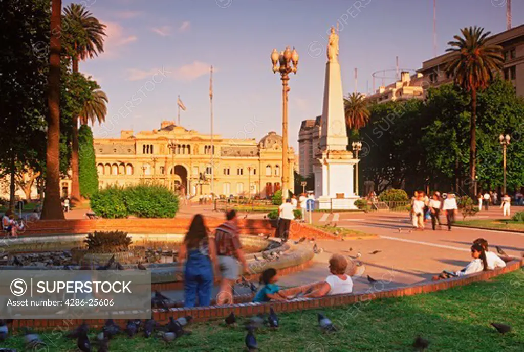Casa Rosada Palace beyond statue on Plaza de Mayo at sunset in Buenos Aires