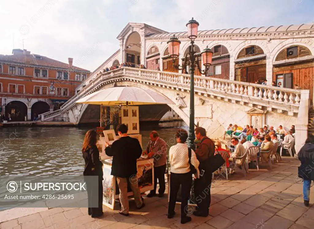 Cafe and tourists on Grand Canal at Rialto Bridge in Venice