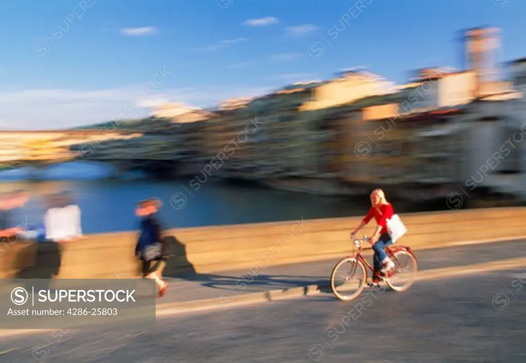 Female biking on Ponte St Trinita over Arno River in Florence