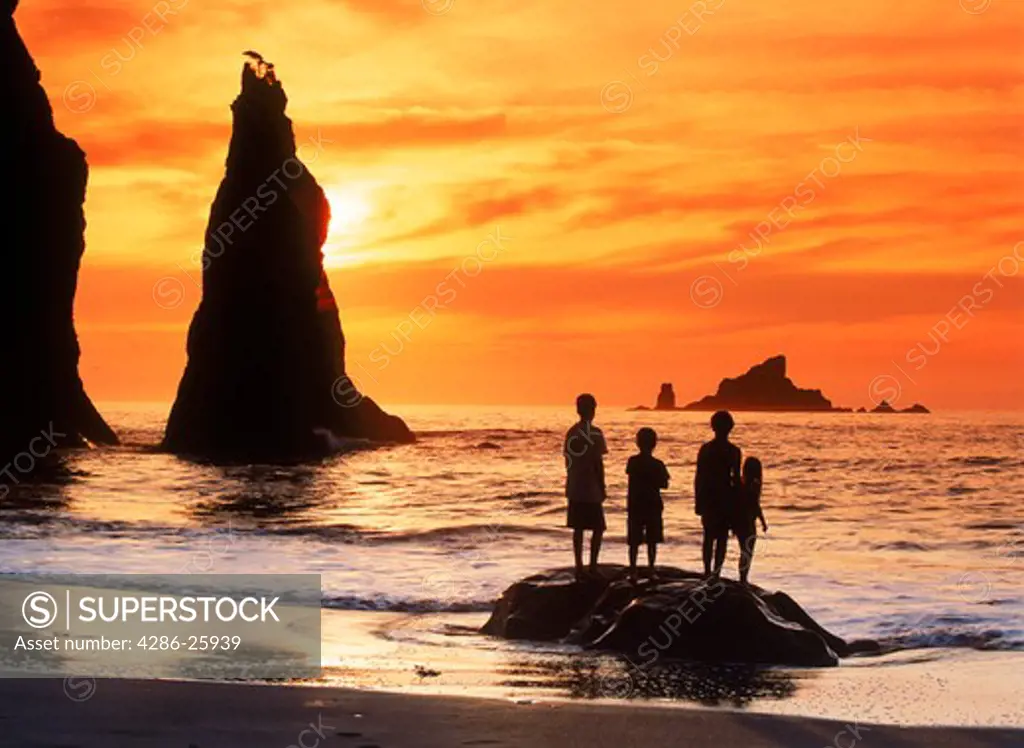 Three children on rock at sunset with seastacks at Olympic National Park