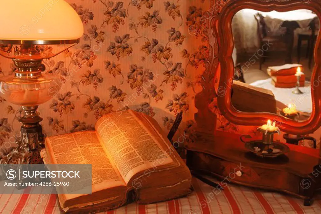 Old Bible sitting on antique bureau under lamp 