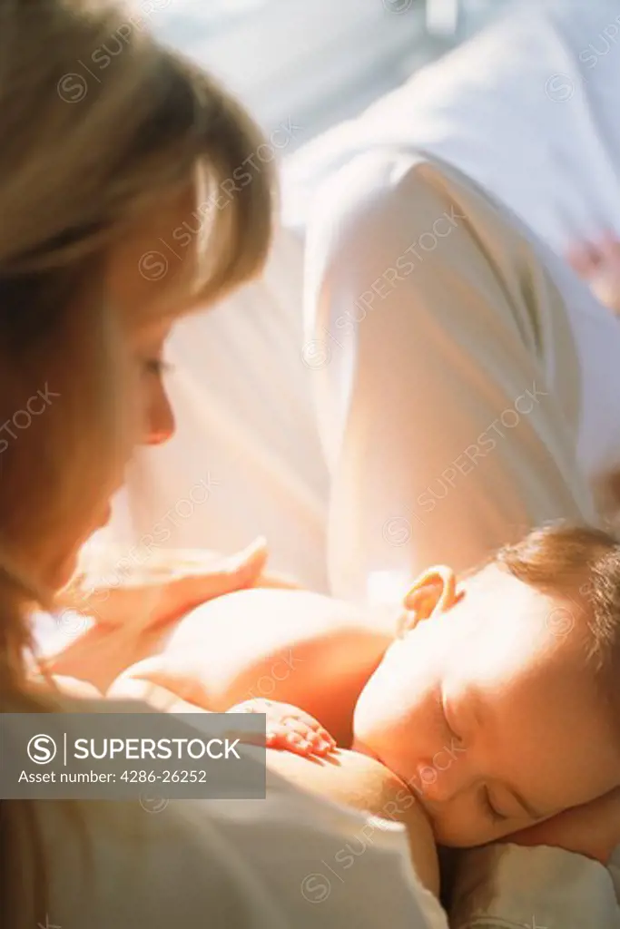 Mother breast feeding baby in soft bedroom light