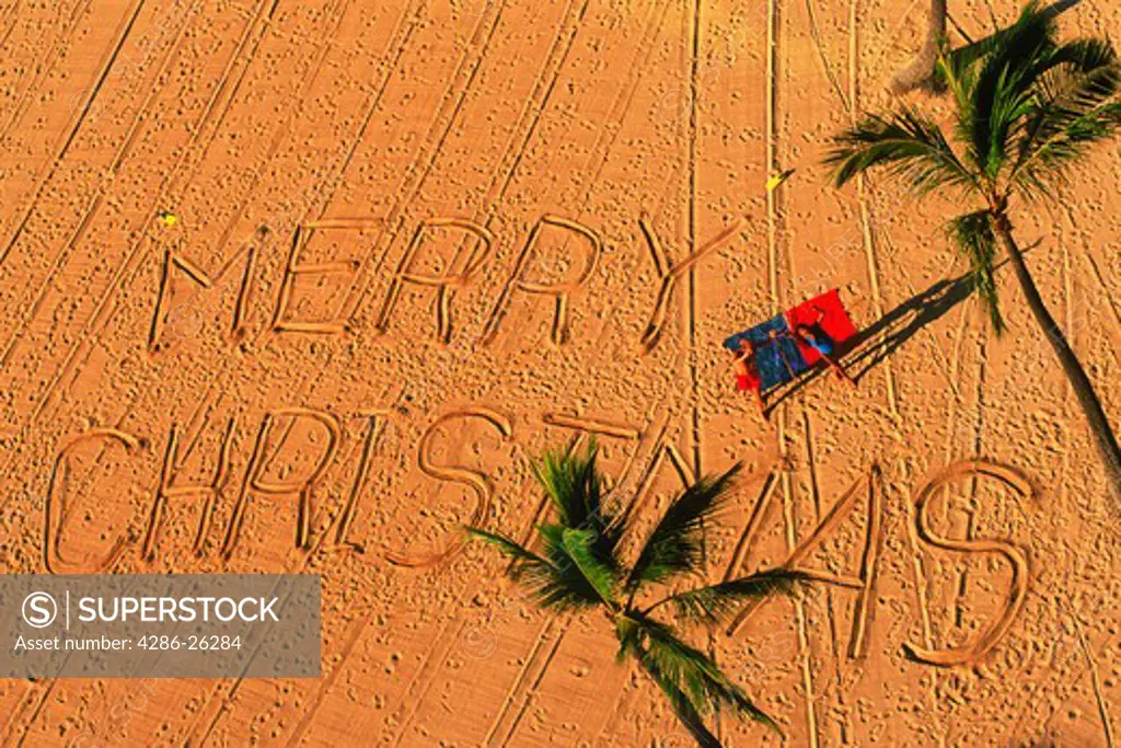 Merry Christmas written on sandy beach in Hawaii
