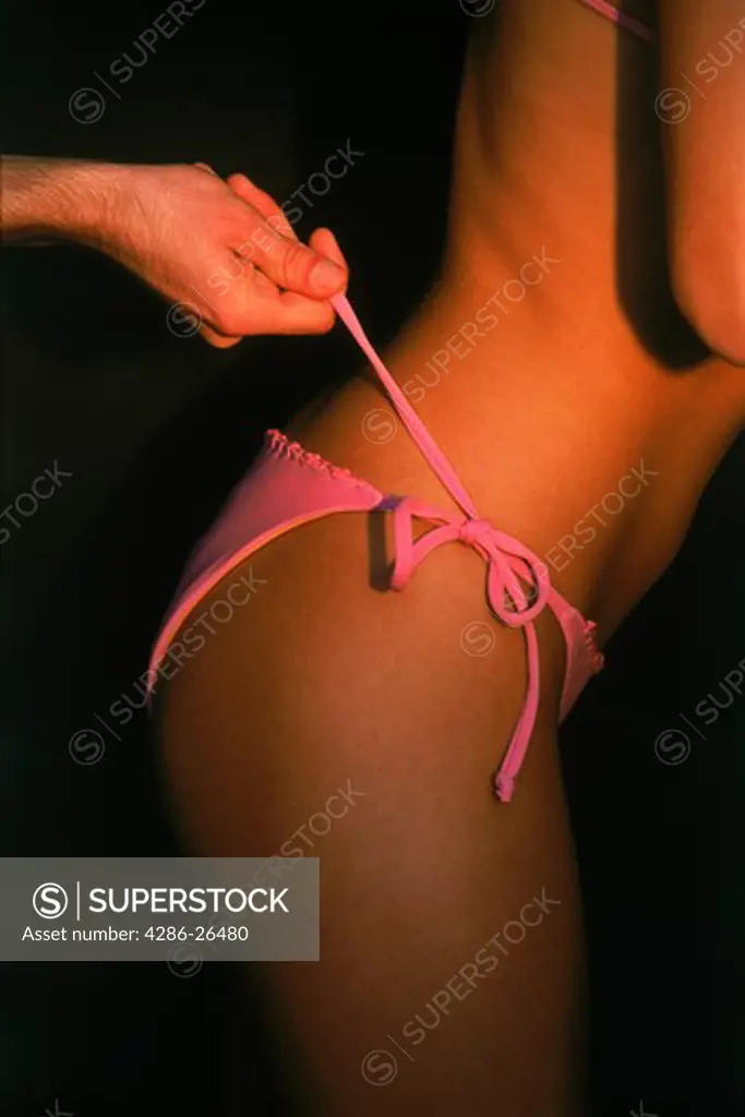 Man untieing womans pink bikini 
