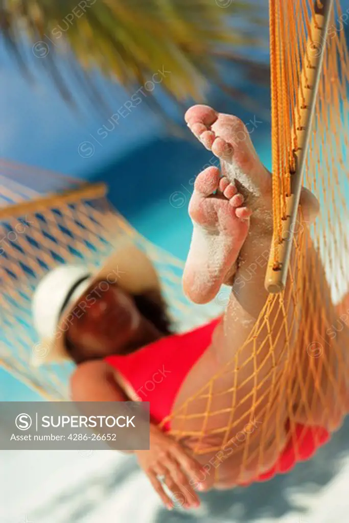 Lady in red swimsuit relaxing in beach hammock 