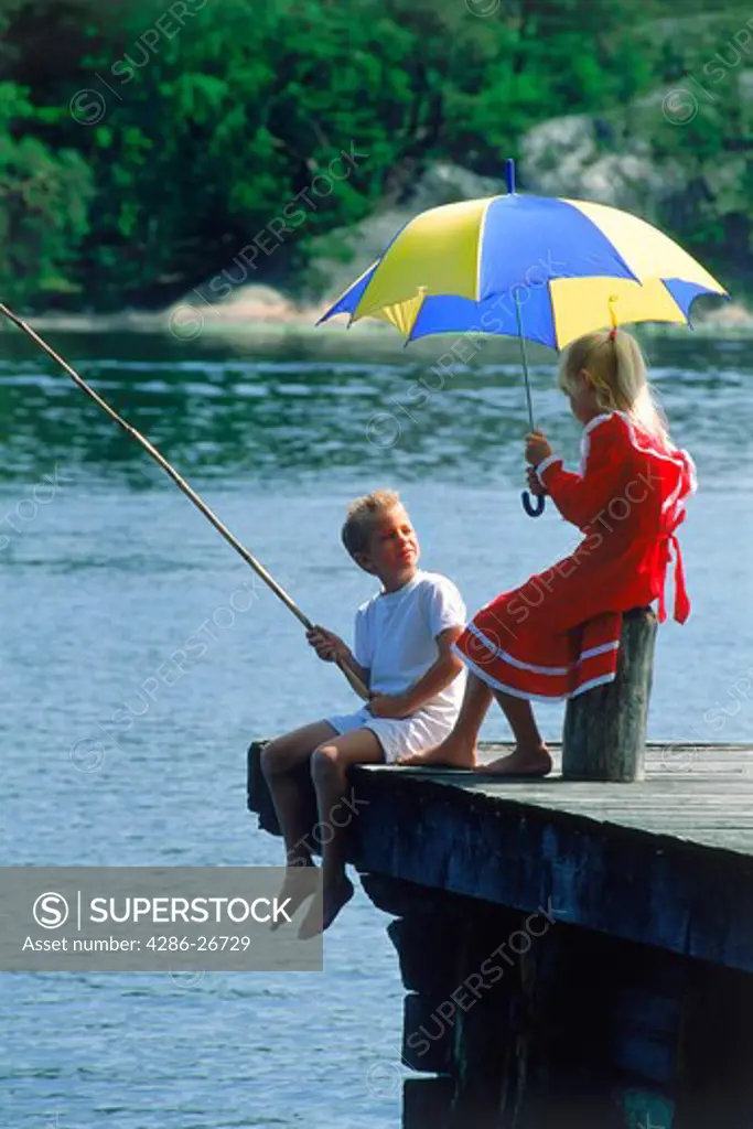 Children fishing off pier under umbrella with Swedish colors