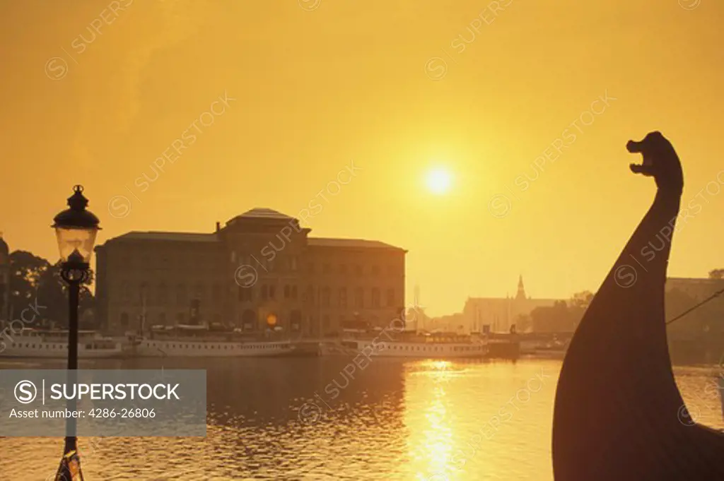 Viking ship bow and lamp post on Skeppsbron in Stockholm at sunrise with National Museum 