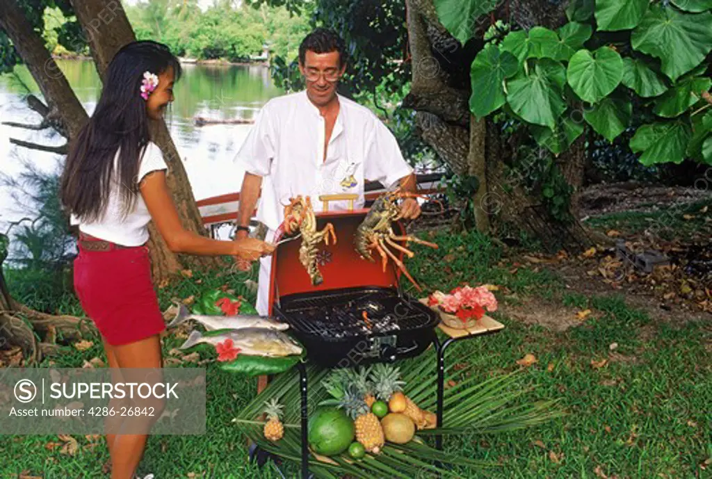 Friends grilling lobster on backyard barbeque in French Polynesia