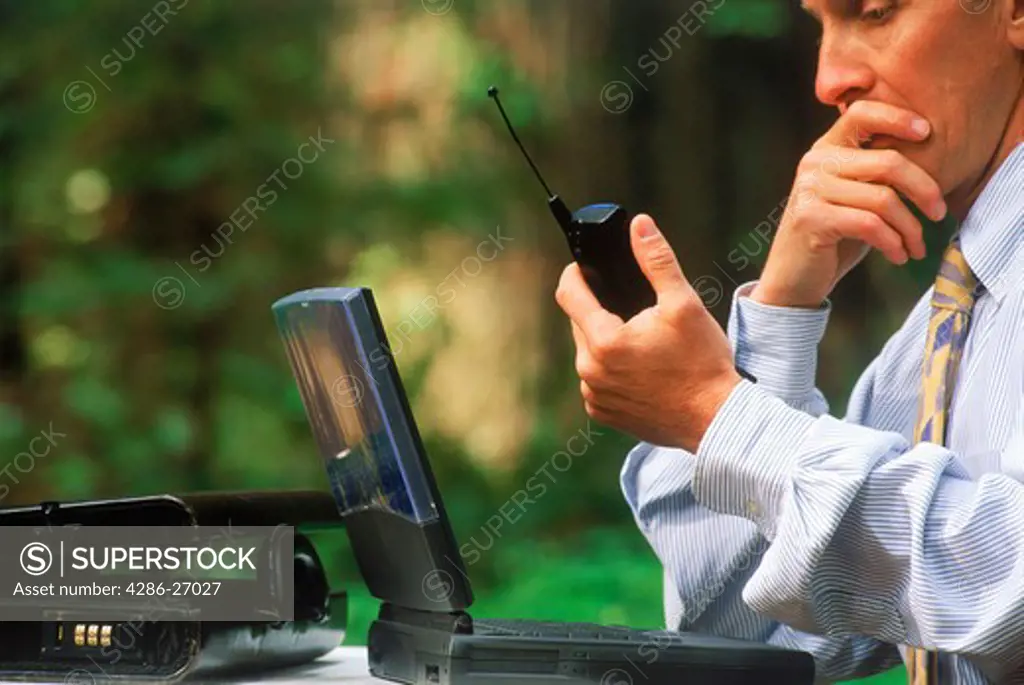 Businessman with laptop and cellphone working outdoors