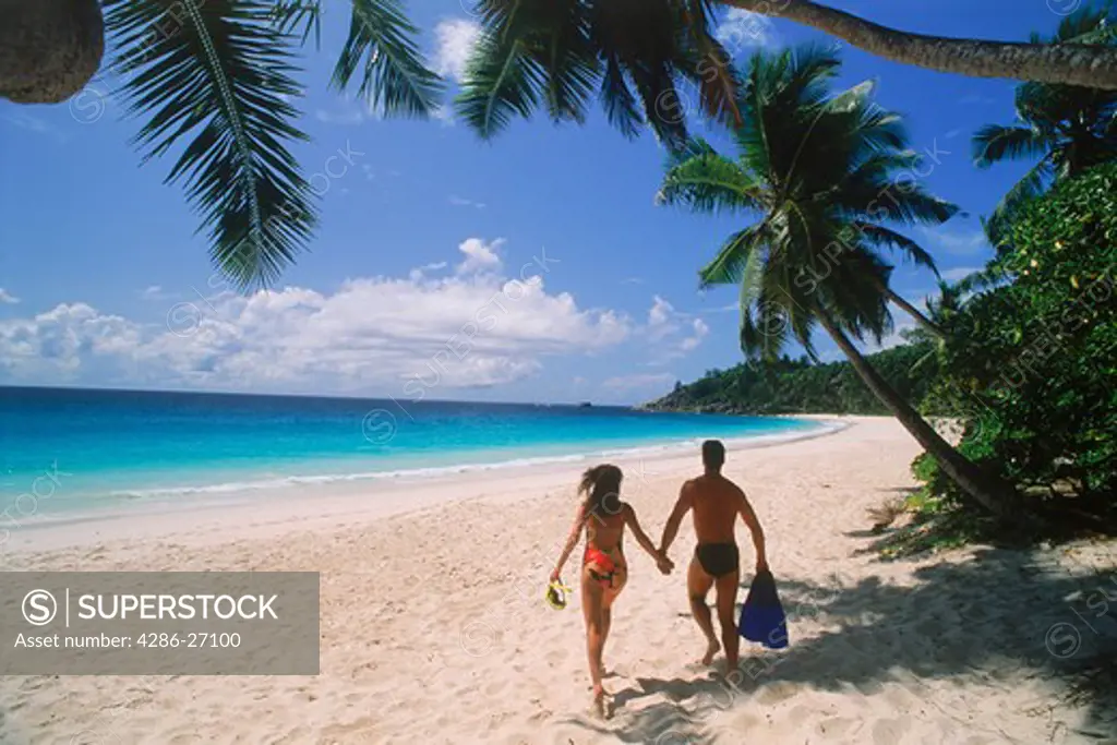 Couple running across Intendence Beach on Mahe Island in Seychelles