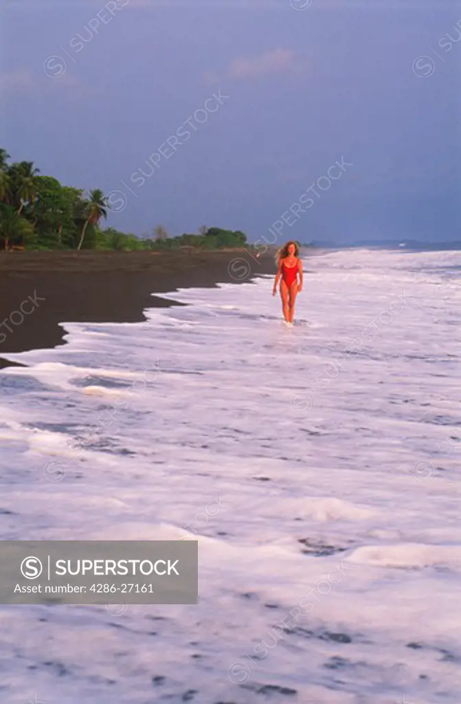 Woman on black lava shores of Playa Hermosa on Pacific Coast of Costa Rica