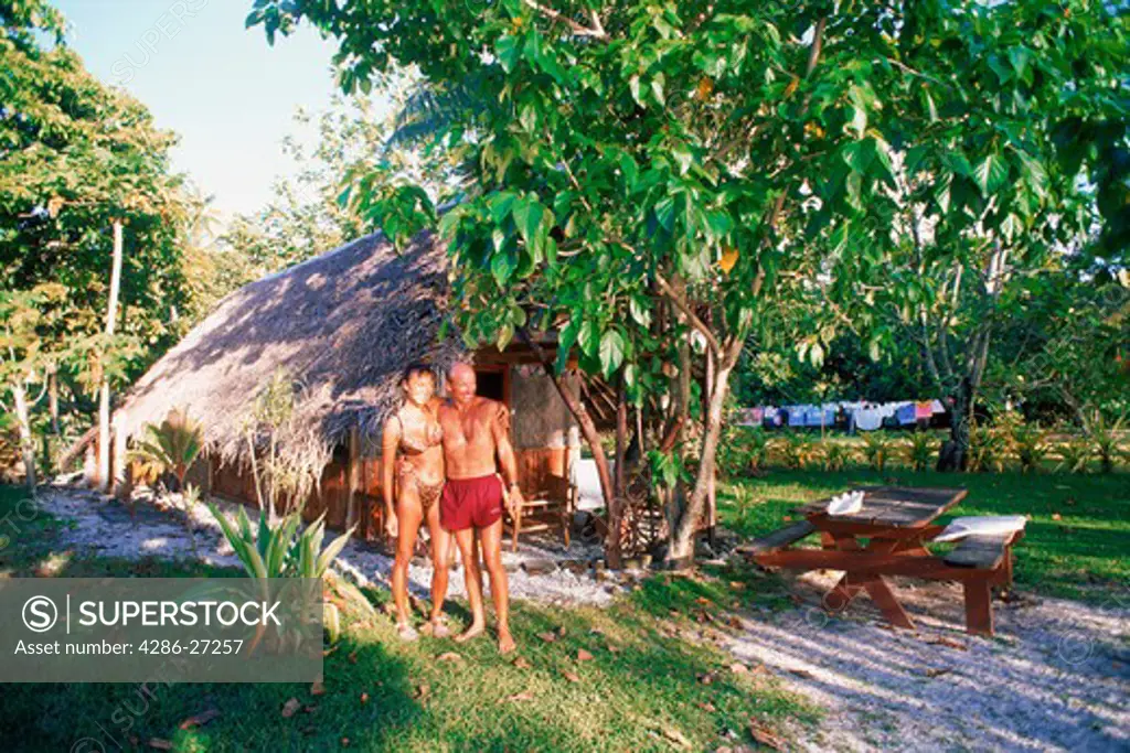 Couple at native hut on Huahine Island in sunset light