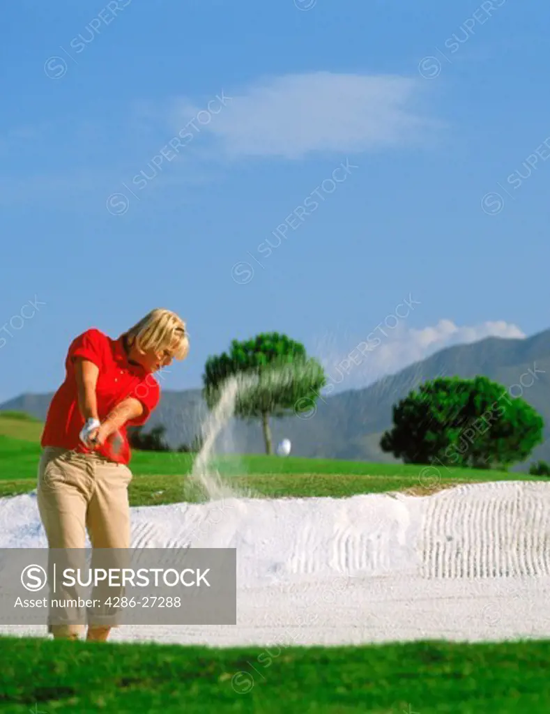 Woman golfer hitting out of bunker