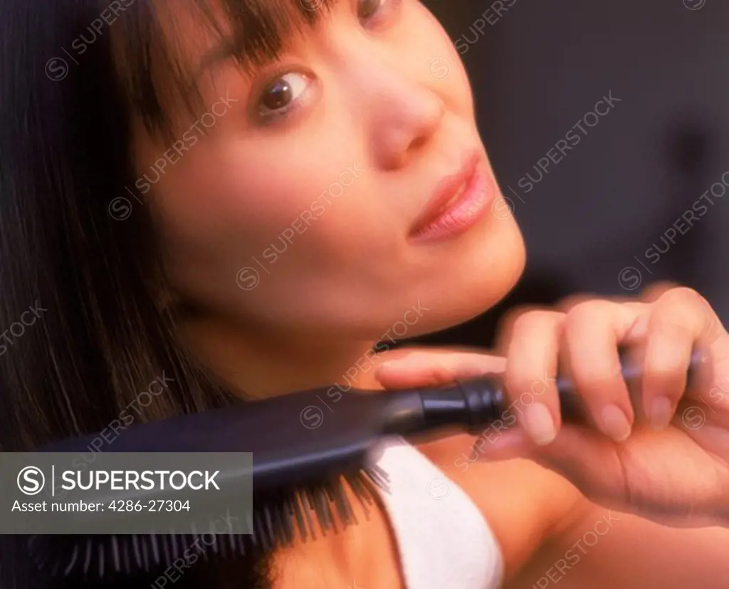 Close up of Asian woman brushing long black hair