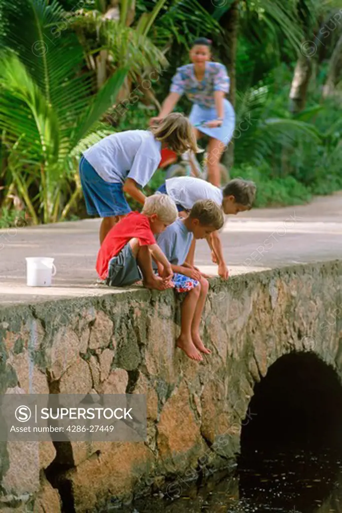 Boys fishing off rock bridge in Seychelles