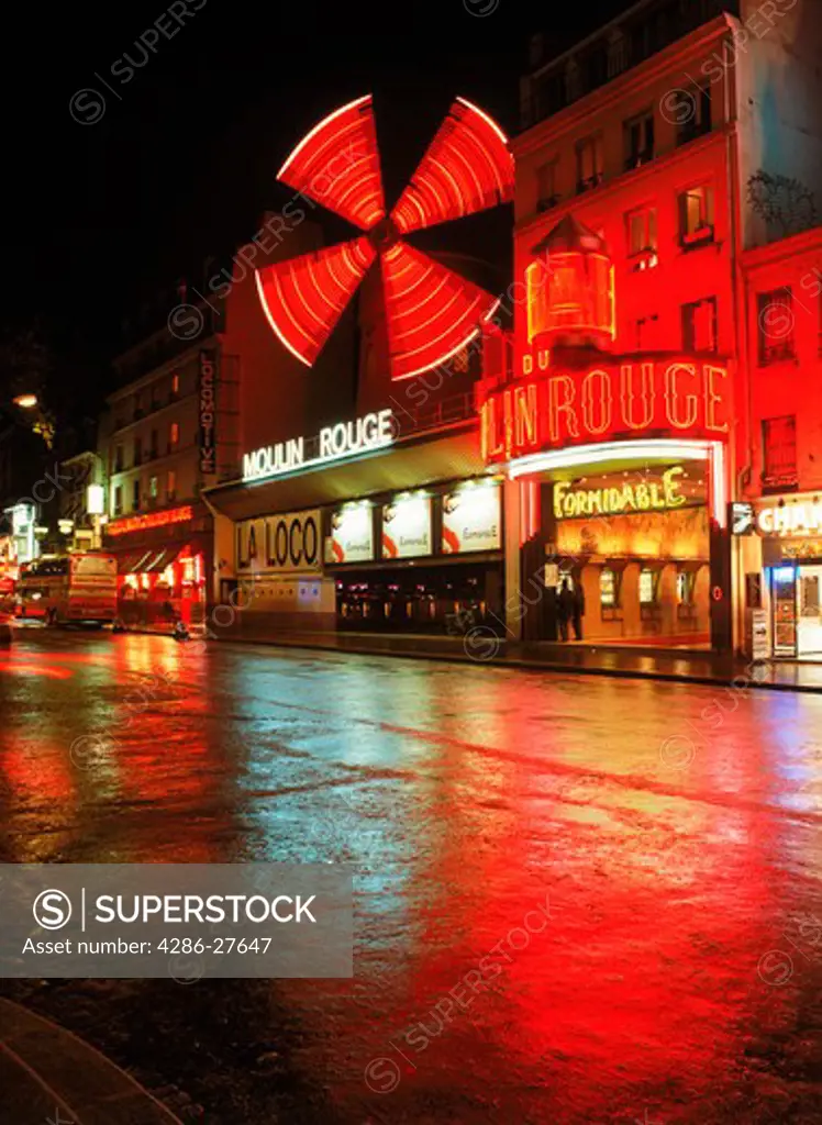 Moulin Rouge reflecting off wet street in Pigalle district of Paris at night