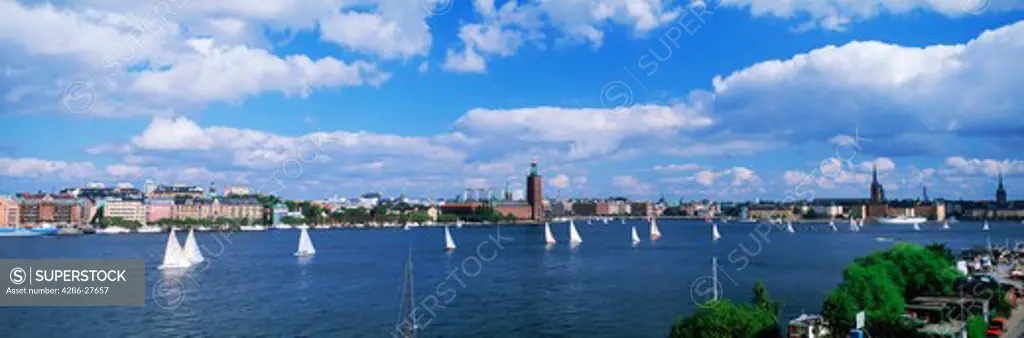 Sailboats on Riddarfjarden waters with Stockholm City Hall and skyline in summer