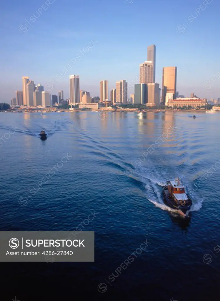 Fishing boats leaving Singapore harbour under city skyline at sunrise