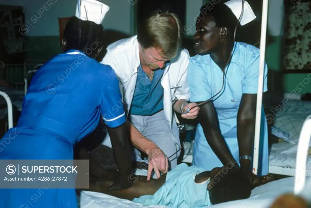 Male doctor performing intra paritoneal blood transfusion for African child at mission hospital in Kenya