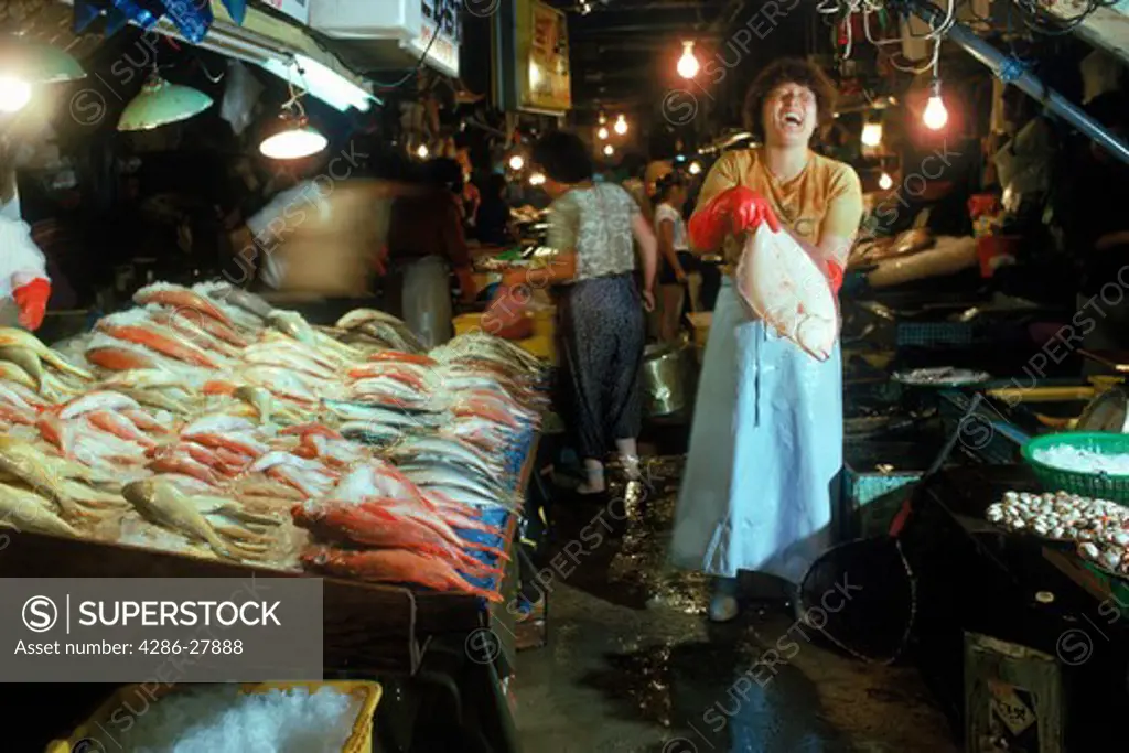 Lady holding halibut or sole at fish market at port of Pusan in South Korea