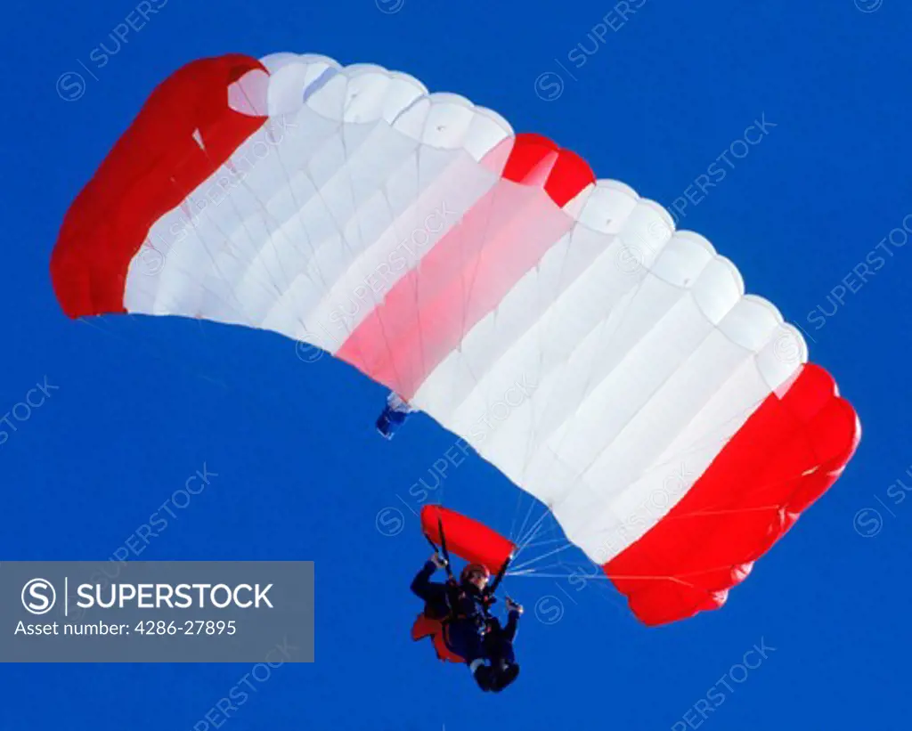 Parachute floating gracefully earthward against blue sky
