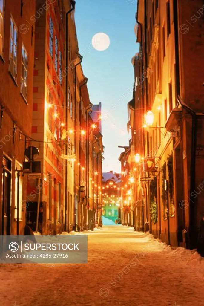Full moon over snow on Svartmangatan with Christmas decorations in Stockholms Old Town