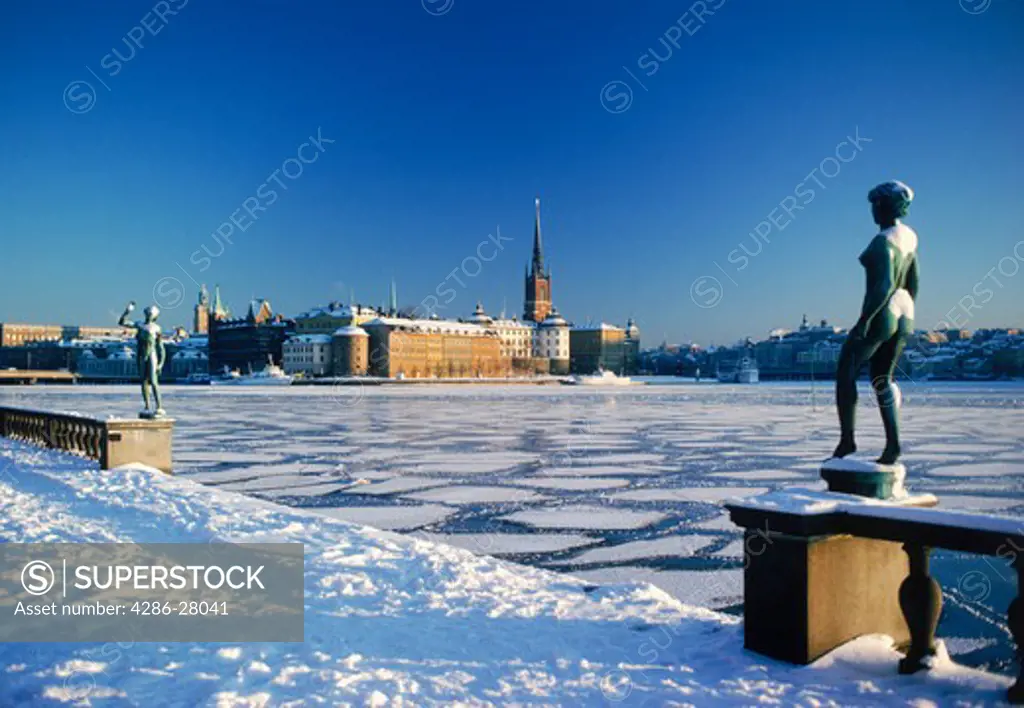 Winter snow and ice on frozen Riddarfjarden with statue in front of Stockholm City Hall
