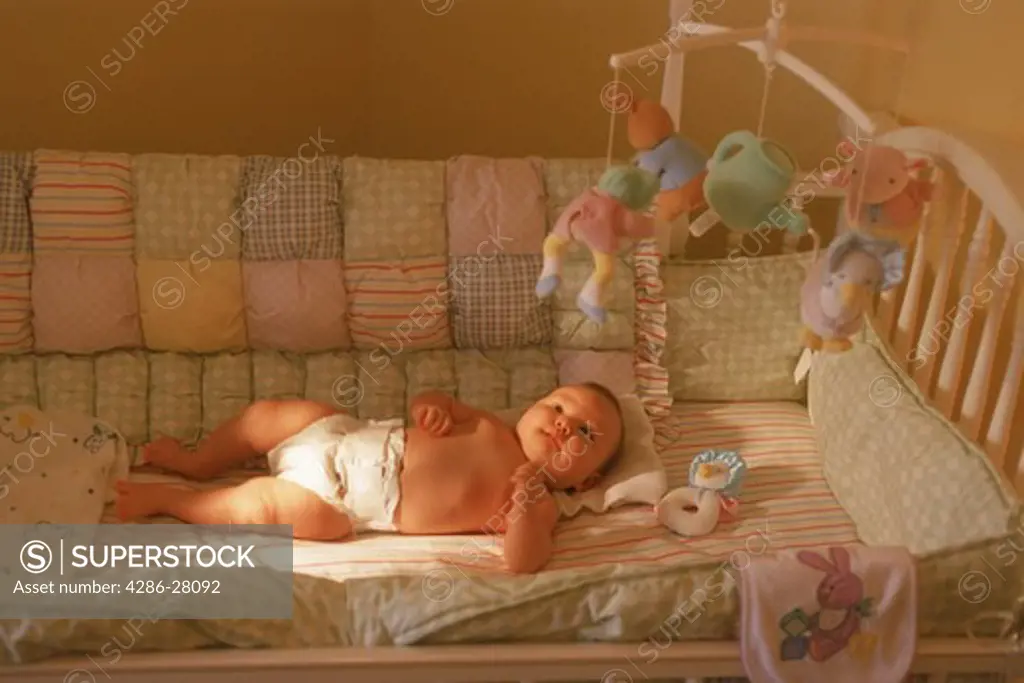 Baby in bassinet with toys hanging overhead