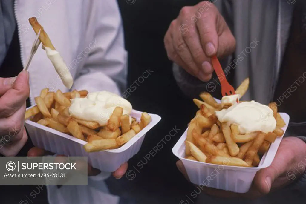 Couple eating French fries or pommes frites with mayonnaise