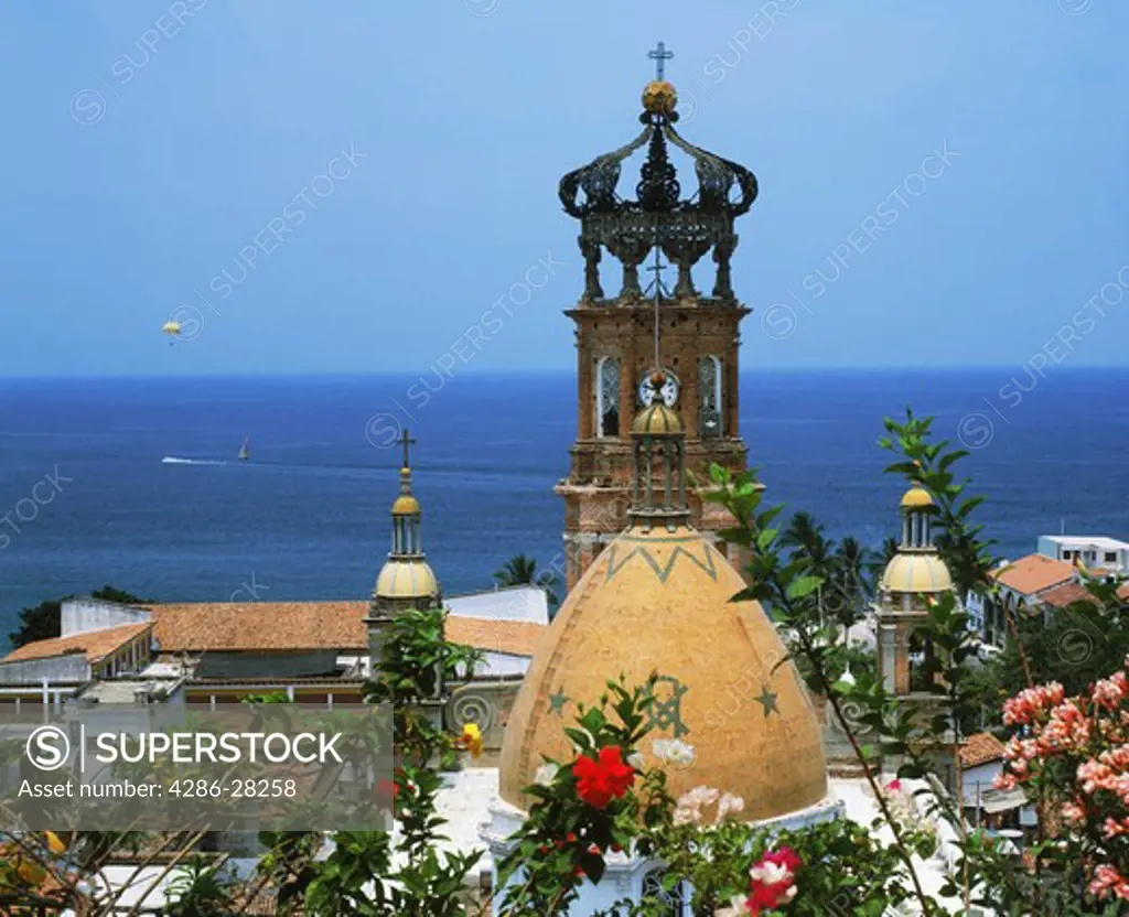 Guadalupe Church bell tower with flowers and Pacific Ocean in Puerto Vallarta Mexico