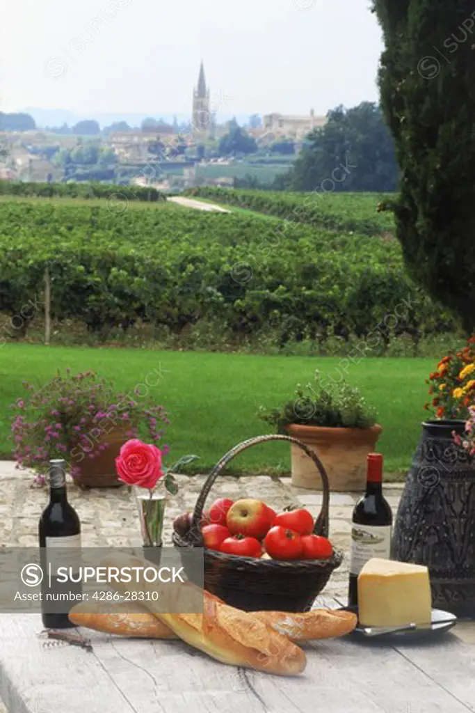 French wine, bread and cheese with vineyards of Saint Emilion and village church beyond