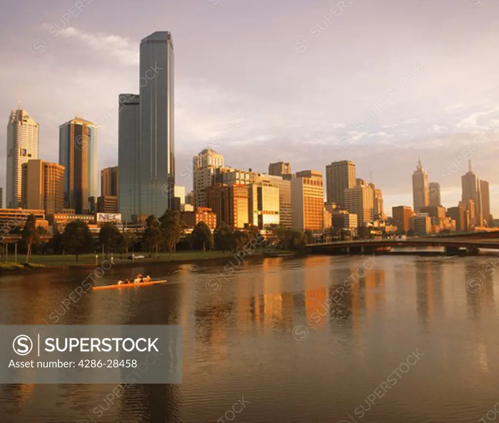 Central Business District reflecting off Yarra River in Melbourne at sunrise with passing scull or racing shell