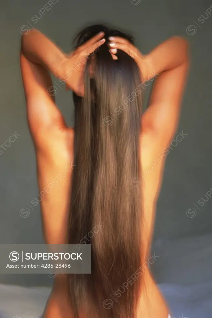 Back view of  nude woman with long dark hair in relaxed sensual pose