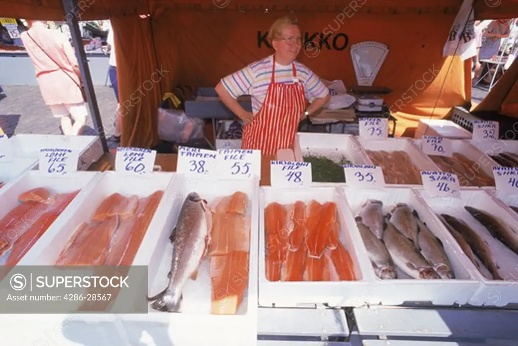 Female merchant selling fresh fish in outdoor market place at South Harbor in Helsinki