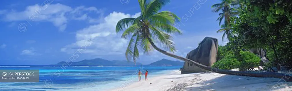 Couple walking along sandy shore at Anse dArgent on La Digue Island in Seychelles