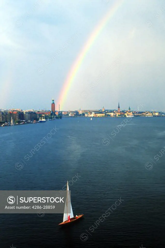 Sailboat on Riddarfjarden waters with rainbow hitting Stockholm City Hall (Stadshuset)