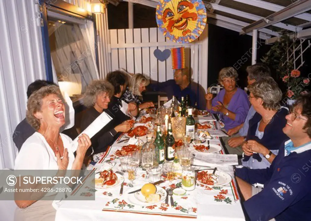 Swedes laughing singing and drinking at traditional crayfish party