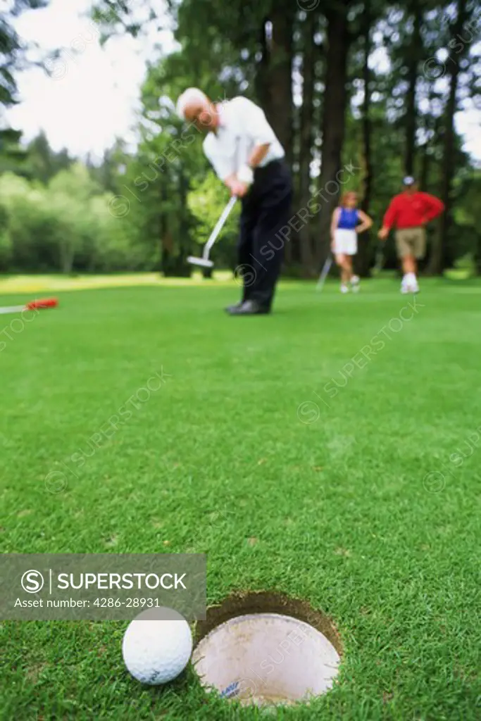 Golf ball hanging on edge of hole after long putt