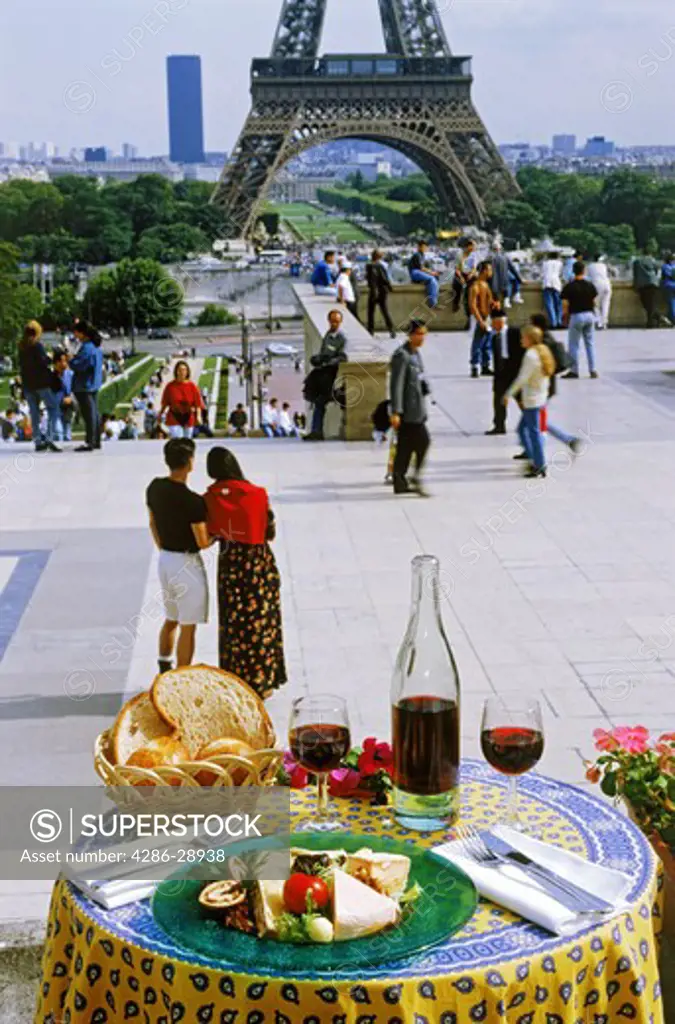 French wine, cheese, bread and tablecloth at Trocadero restaurant with Eiffel Tower and passing tourists