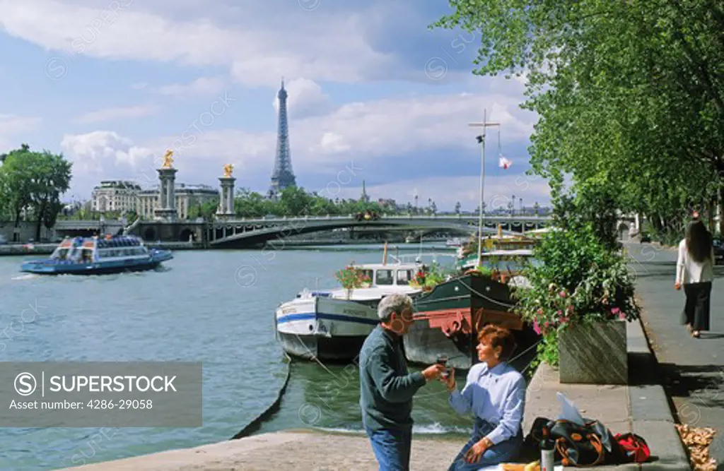 Couple having picnic on River Seine with Eiffel Tower