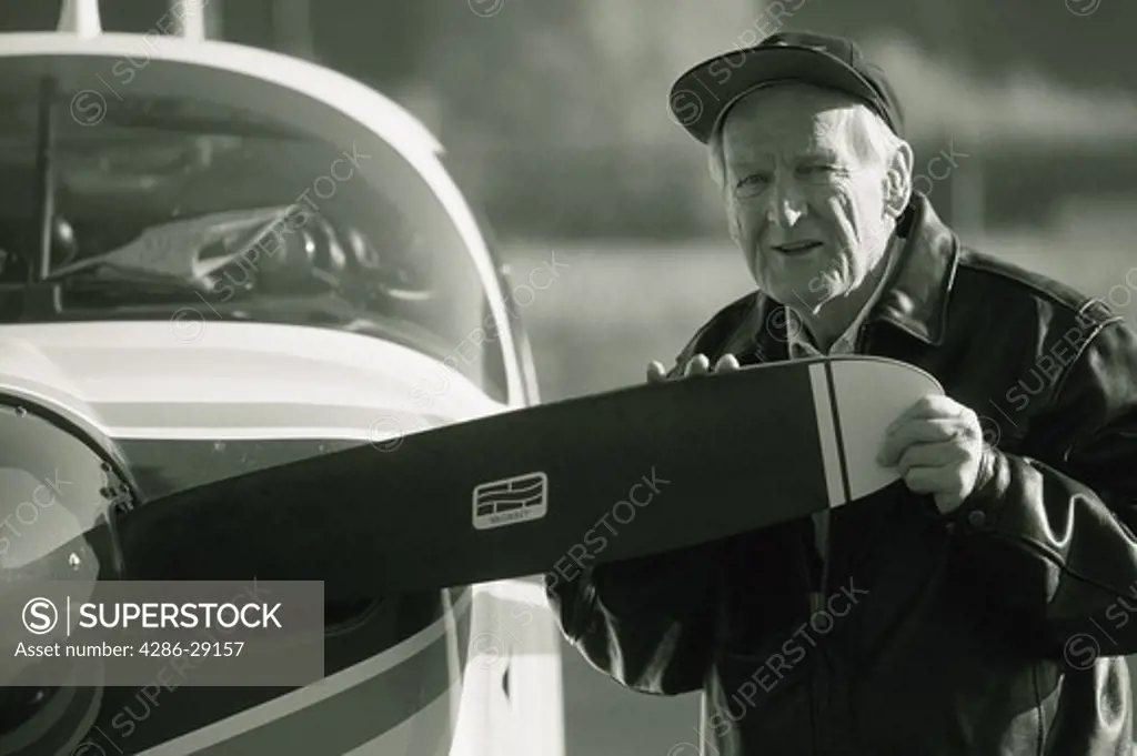 A senior man examines the edge of the propeller to his single engine private plane.