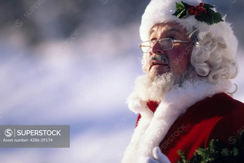 Portrait of a man dressed as Santa Claus looks skyward while standing outdoors.
