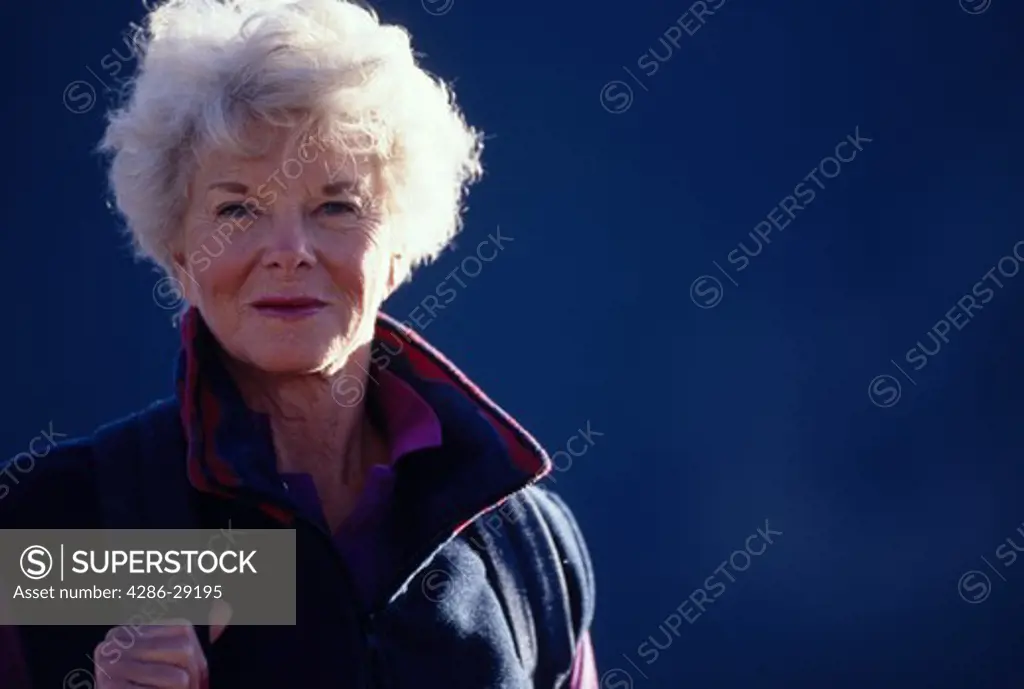 Portrait of a senior woman in hiking clothes outdoors on a cool sunny day.