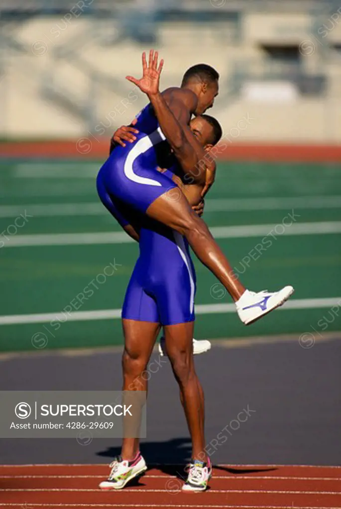 A runner jumps into his teammates arms as they celebrate after a victory.