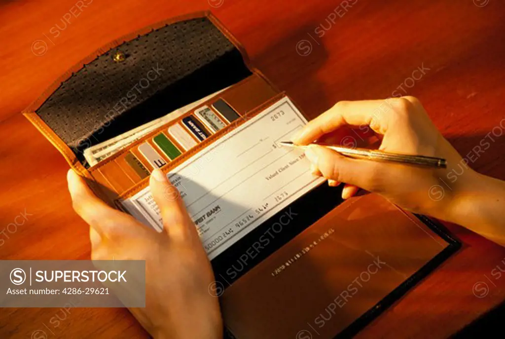 Close-up of a woman's hands as she writes a check.